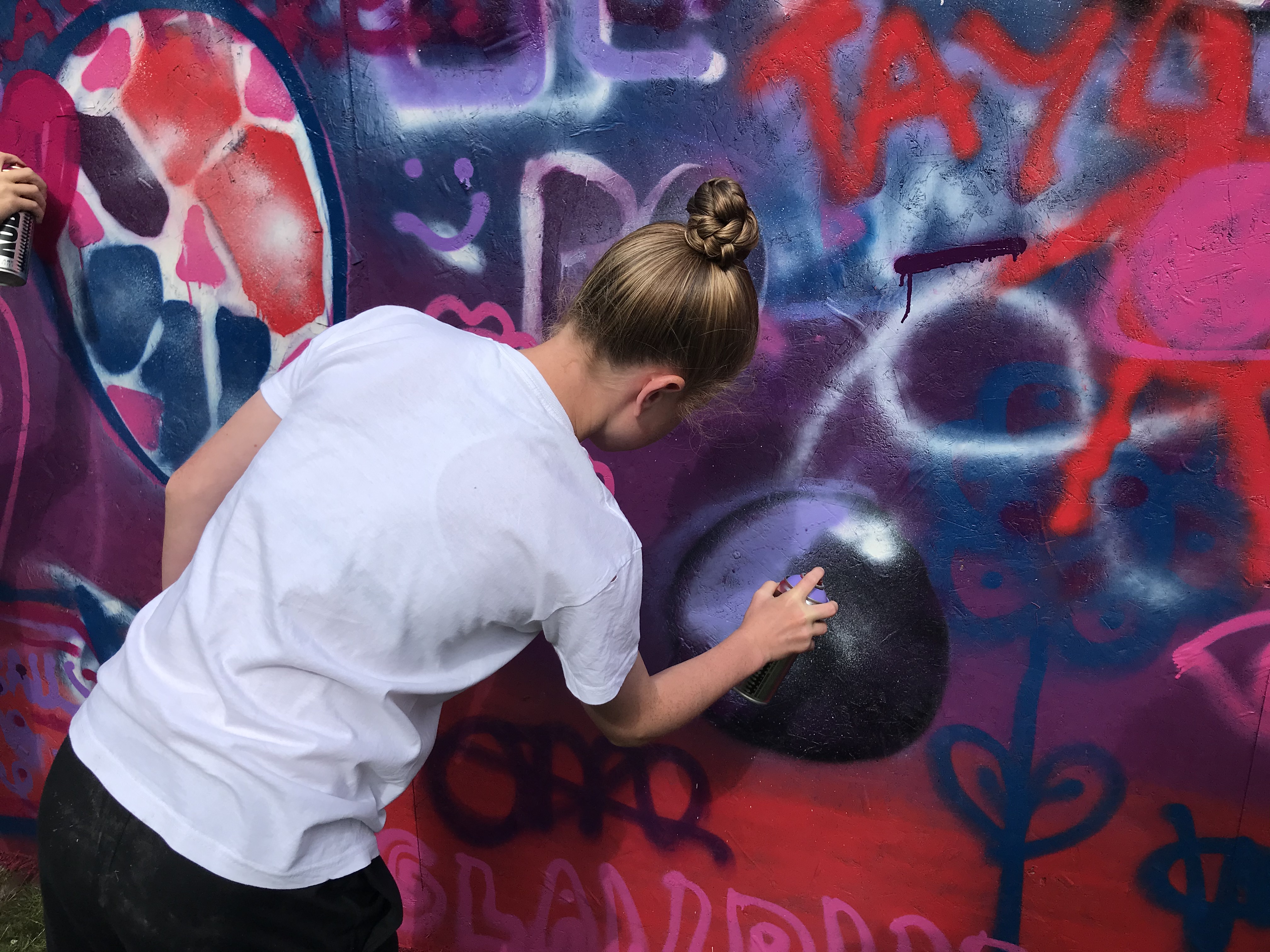 A young woman is spray painting a football inspired mural